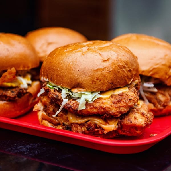 Bird On The Run fried chicken sandwiches with cheese and lettuce on a red tray.